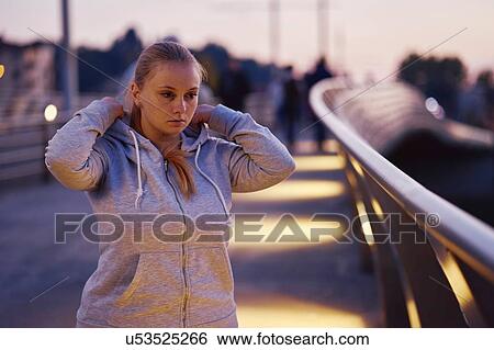 Curvaceous young woman training, getting hoody ready on footbridge at dusk View Large Photo Image Stock Photograph - Curvaceous young woman training, getting hoody ready on footbridge at dusk. Fotosearch