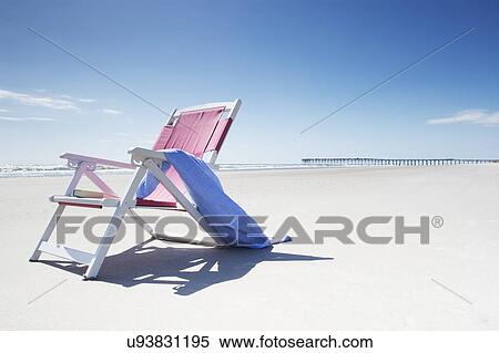 Stock Photography - Deck chair with towel on sandy beach by Atlantic Ocean. Fotosearch