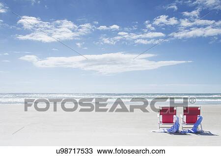 Stock Image - Deck chairs with towels on sandy beach by Atlantic Ocean. Fotosearch