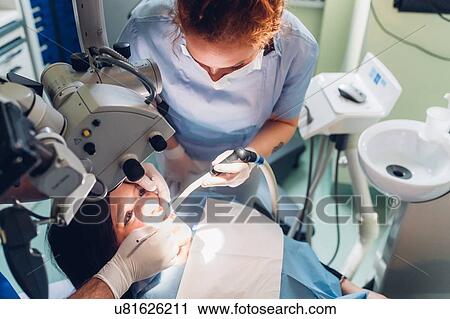 Stock Image - Dentist and dental nurse carrying out dental procedure on female patient. Fotosearch