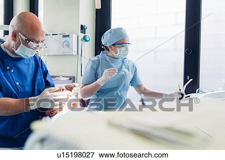 Dentist and dental nurse carrying out dental procedure on male patient, close-up View Large Photo Image Stock Photo - Dentist and dental nurse carrying out dental procedure on male patient, close-up. Fotosearch