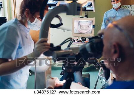 Dentist and dental nurse carrying out procedure on patient View Large Photo Image Stock Photo - Dentist and dental nurse carrying out procedure on patient. Fotosearch