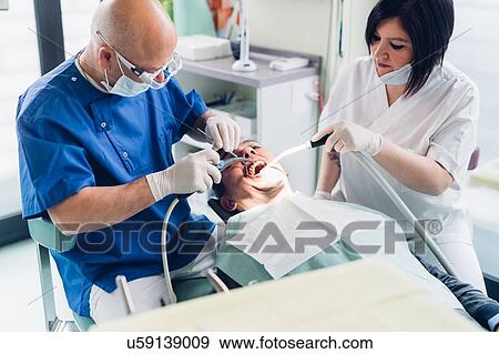 Dentist and dental nurse carrying out procedure on male patient View Large Photo Image Stock Photo - Dentist and dental nurse carrying out procedure on male patient. Fotosearch