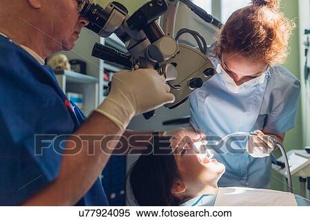 Stock Photography - Dentist and dental nurse carrying out dental procedure on female patient. Fotosearch