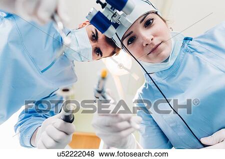 Dentist and dental nurse treating patient, personal persepctive View Large Photo Image Stock Photo - Dentist and dental nurse treating patient, personal persepctive. Fotosearch