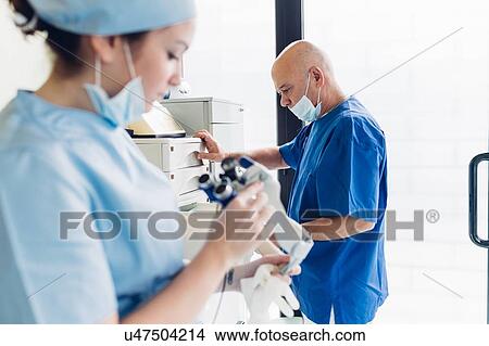 Picture - Dentist and dental nurse working in dentist office. Fotosearch