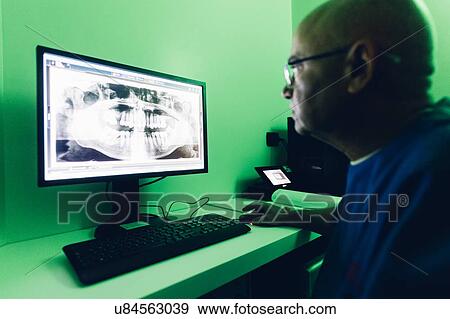 Stock Photo - Dentist looking at dental x-ray on computer. Fotosearch