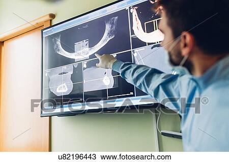 Stock Image - Dentist looking at dental x-rays, focus on background. Fotosearch