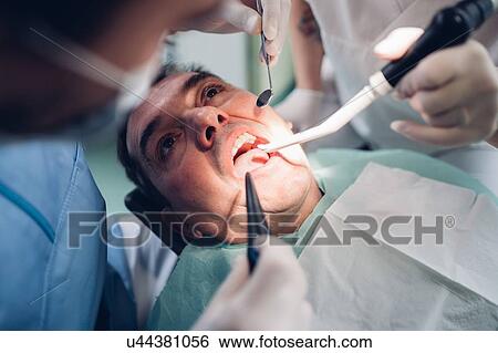 Dentist looking into male patient's mouth, elevated view View Large Photo Image Stock Photograph - Dentist looking into male patient's mouth, elevated view. Fotosearch