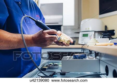 Stock Image - Dentist making denture in laboratory, mid section. Fotosearch
