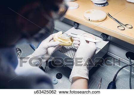 Stock Image - Dentist making denture in laboratory. Fotosearch