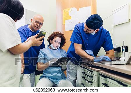 Dentists in dentist office looking at digital tablet, laptop and smartphone View Large Photo Image Stock Image - Dentists in dentist office looking at digital tablet, laptop and smartphone. Fotosearch