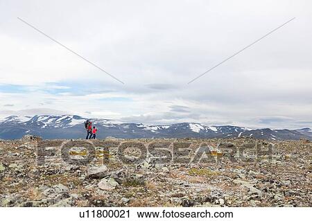 Stock Image - Distant view of man with sons hiking mountain landscape, Jotunheimen National Park, Lom, Oppland, Norway. Fotosearch