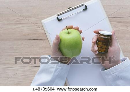Picture - Doctor advising apple instead of pills.. Fotosearch