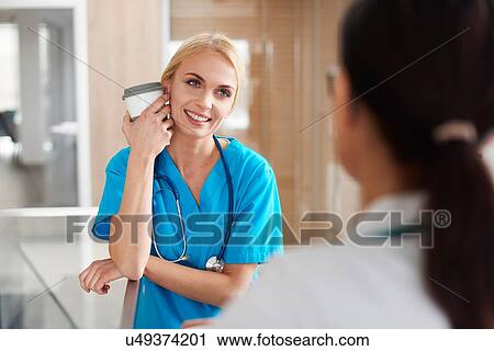 Stock Image - Doctor and surgeon talking in hallway. Fotosearch