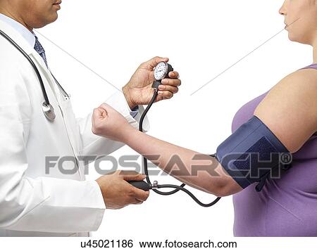 Doctor checking woman's blood pressure. View Large Photo Image Stock Photograph - Doctor checking woman's blood pressure.. Fotosearch