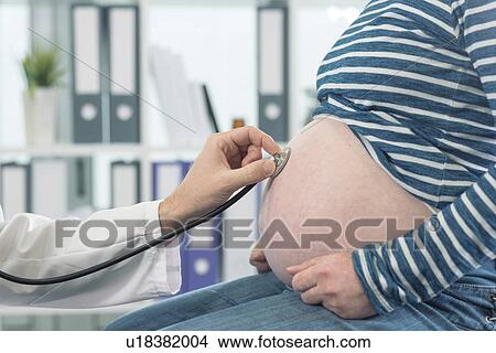 Doctor examining pregnant woman with stethoscope. View Large Photo Image Picture - Doctor examining pregnant woman with stethoscope.. Fotosearch