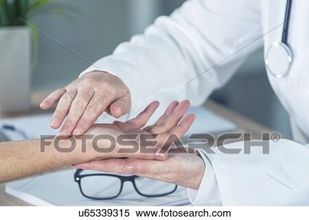 Stock Photography - Doctor examining woman's wrist.. Fotosearch