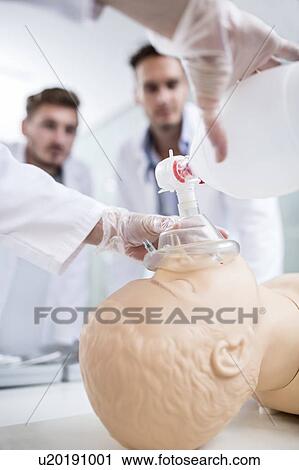 Stock Image - Doctor practising bag-valve-mask ventilation on a training dummy.. Fotosearch
