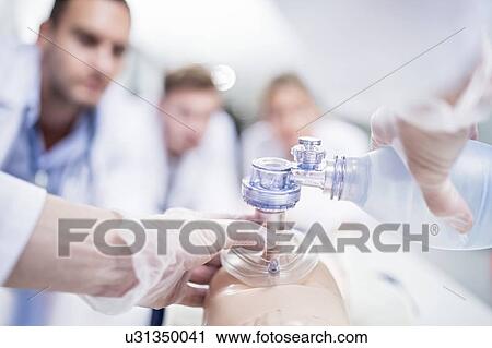 Stock Image - Doctor practising bag-valve-mask ventilation on a training dummy.. Fotosearch