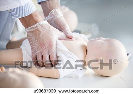 Doctor practising chest compressions on an infant CPR training dummy. View Large Photo Image Stock Photo - Doctor practising chest compressions on an infant CPR training dummy.. Fotosearch