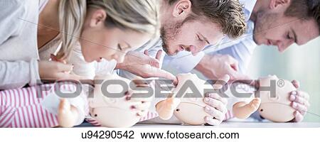 Stock Image - Doctor practising infant CPR on training dummies.. Fotosearch