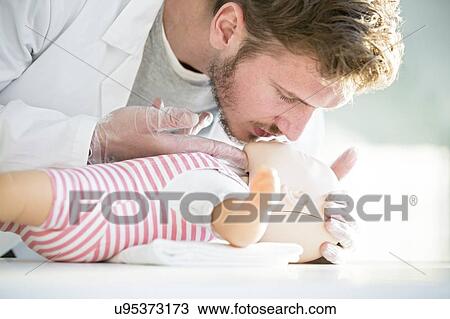 Stock Image - Doctor practising infant CPR on training dummies.. Fotosearch