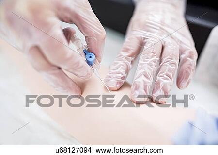 Picture - Doctor practising inserting an IV (intravenous) line on a training dummy.. Fotosearch