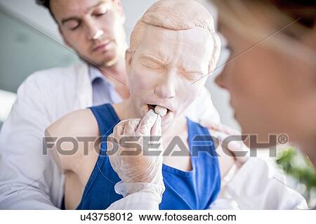 Stock Image - Doctor practising the Heimlich manoeuvre on a training dummy.. Fotosearch
