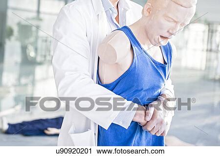 Doctor practising the Heimlich manoeuvre on a training dummy. View Large Photo Image Stock Image - Doctor practising the Heimlich manoeuvre on a training dummy.. Fotosearch