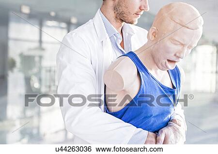 Doctor practising the Heimlich manoeuvre on a training dummy. View Large Photo Image Stock Photograph - Doctor practising the Heimlich manoeuvre on a training dummy.. Fotosearch