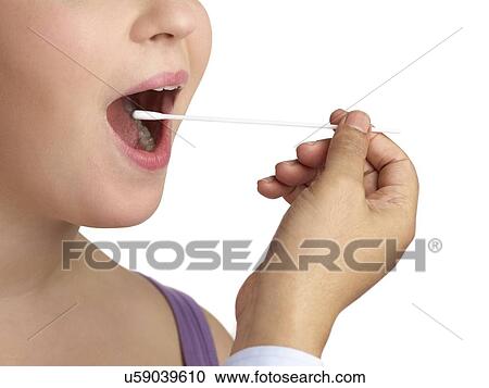 Stock Image - Doctor taking a swab from a woman's mouth.. Fotosearch
