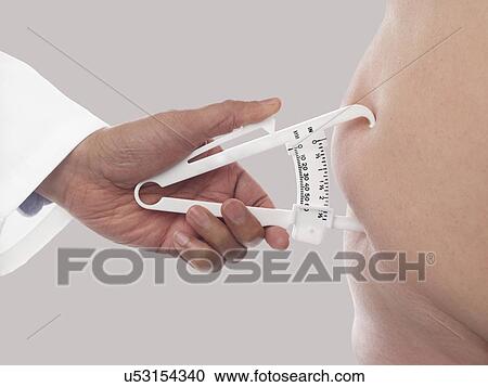 Doctor using a skin fold calliper to measure body fat. View Large Photo Image Stock Image - Doctor using a skin fold calliper to measure body fat.. Fotosearch