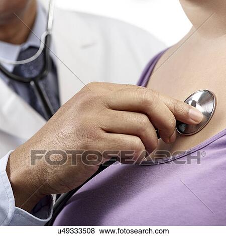 Stock Photo - Doctor using stethoscope to examine woman.. Fotosearch