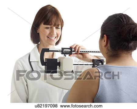 Stock Photo - Doctor weighing woman on scales.. Fotosearch