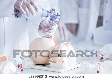Stock Image - Doctors practising tracheal intubation on an infant training dummy.. Fotosearch