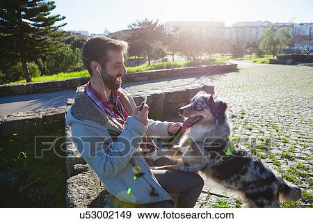 Stock Photo - Dog with paws on owner's lap in park. Fotosearch