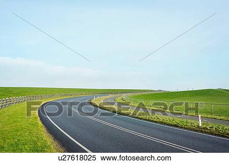 Stock Photography - Empty road through the dyke besides the Waddense, Holwerd, Friesland, Netherlands. Fotosearch