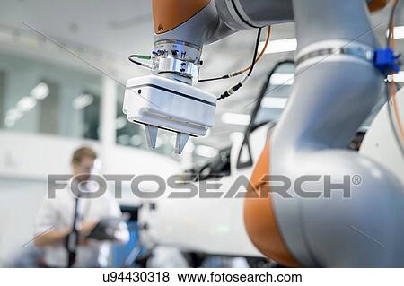 Stock Photo - Engineer and robot inspecting car in robotics research facility. Fotosearch