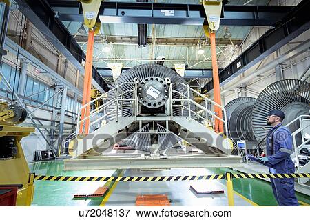 Stock Photo - Engineer operating crane in turbine maintenance factory. Fotosearch