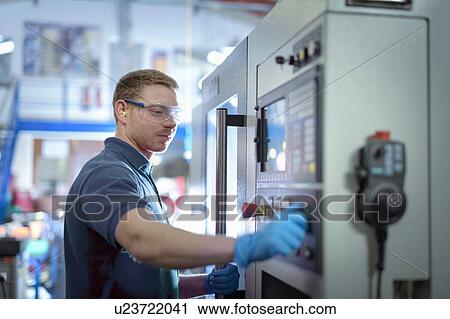 Stock Image - Engineer operating milling machine in precision engineering factory. Fotosearch