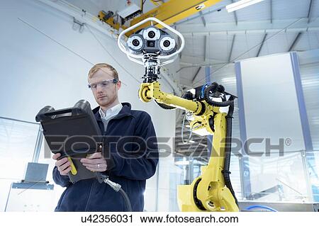 Stock Image - Engineer programming robot in robotics research facility. Fotosearch