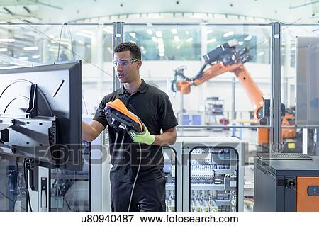 Stock Photo - Engineer programming robot in robotics research facility. Fotosearch