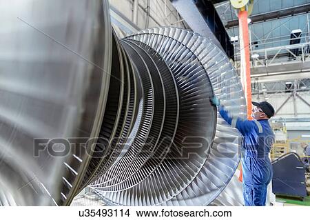 Picture - Engineer turning low pressure steam turbine during inspection in turbine maintenance factory. Fotosearch