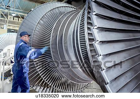 Stock Image - Engineer turning low pressure steam turbine during inspection in turbine maintenance factory. Fotosearch