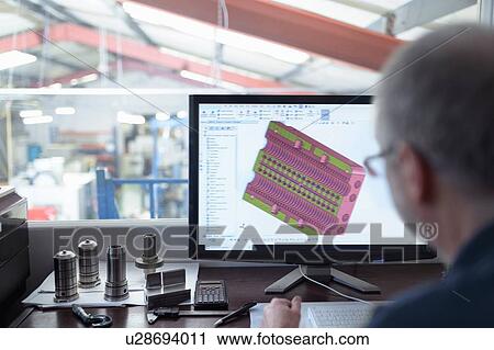 Stock Image - Engineer using CAD program in precision engineering factory. Fotosearch