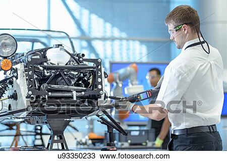 Engineer using computerised tools to assemble car in robotics research facility View Large Photo Image Stock Image - Engineer using computerised tools to assemble car in robotics research facility. Fotosearch