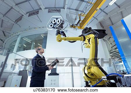 Stock Image - Engineer with robot in robotics research facility, low angle view. Fotosearch
