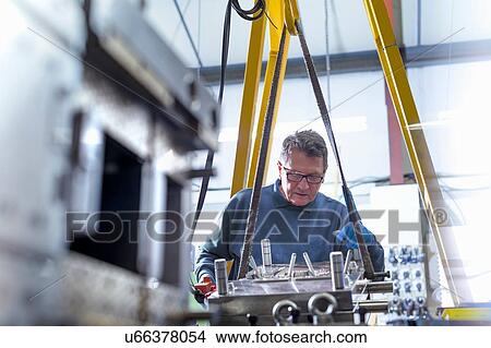 Picture - Engineer working on mould for plastic injection in precision engineering factory. Fotosearch