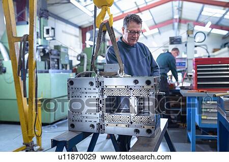 Stock Photo - Engineer working on mould for plastic injection in precision engineering factory. Fotosearch